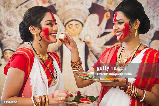 bengali women feeding barfi to each other at durga puja - durga 個照片及圖片檔