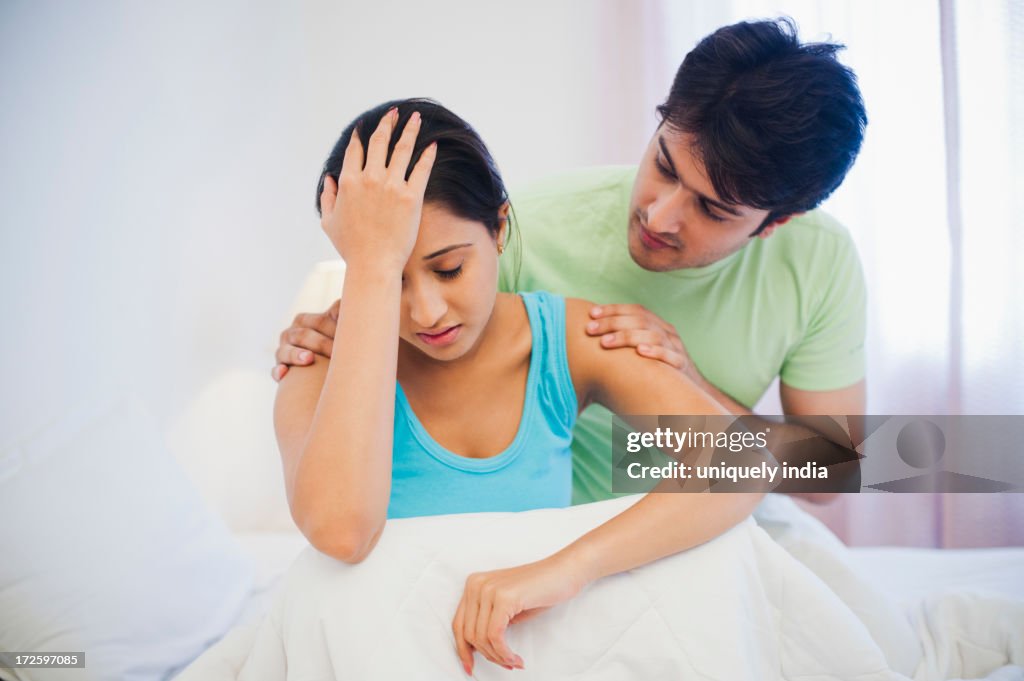 Man persuading his upset wife on the bed