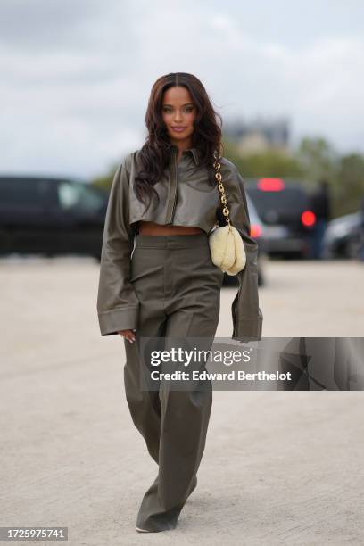 Paola Locatelli wears a green khaki leather jacket, a pastel yellow fluffy Loewe bag, matching flared suit pants, outside Loewe, during the...