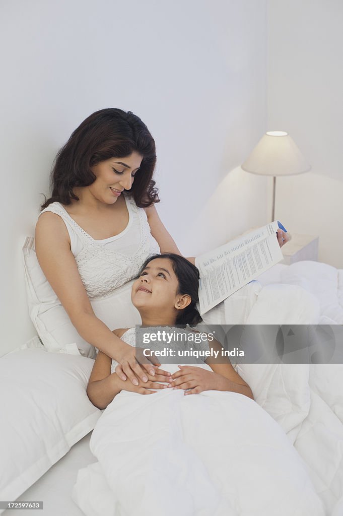 Woman teaching her daughter on the bed