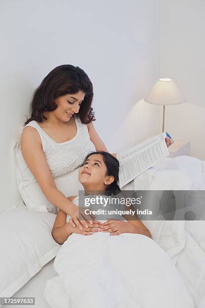 woman teaching her daughter on the bed - bedside table kid asleep stock pictures, royalty-free photos & images