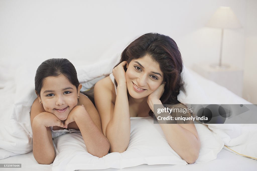 Portrait of a woman with her daughter lying on the bed