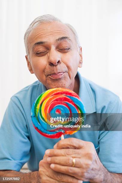 senior man holding a lollipop and making his face - candy on tongue stock pictures, royalty-free photos & images