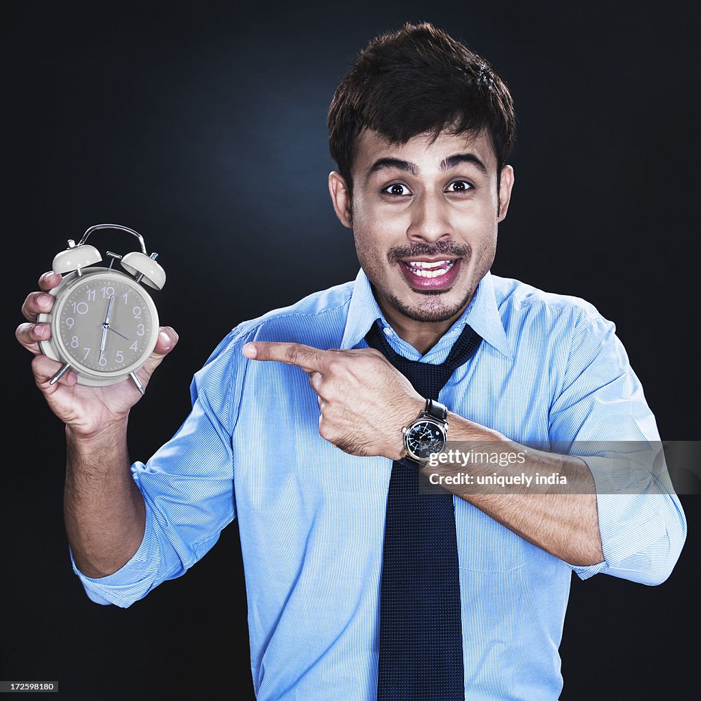 Businessman showing an alarm clock