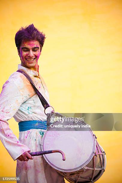 smiling man celebrating holi with playing dhol - dhol drums stock pictures, royalty-free photos & images