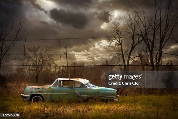 rusted car in dilapidated urban field - detroit ruins stock pictures, royalty-free photos & images