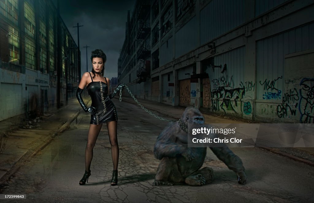Caucasian woman with gorilla on chain on city street