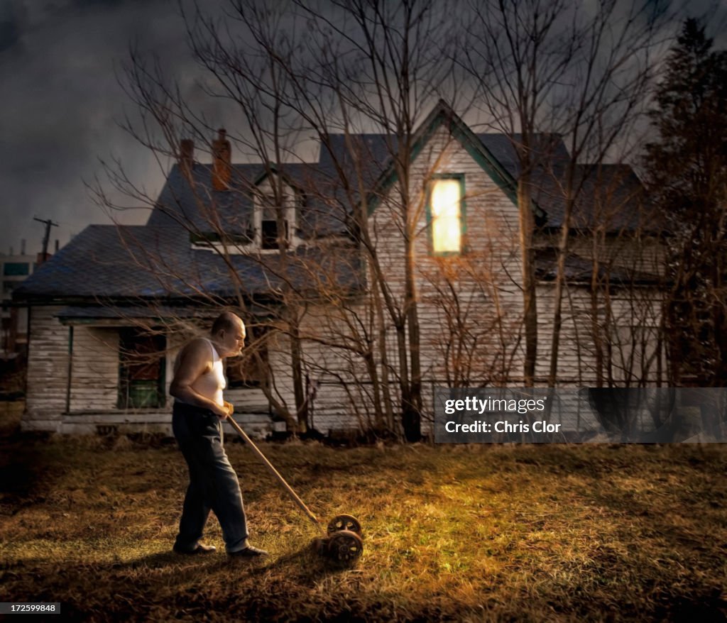 Caucasian man mowing lawn outside home