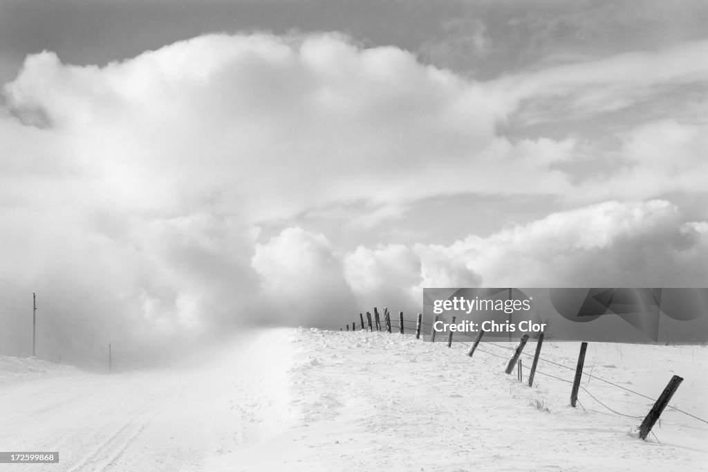 Clouds and wooden fence in snowy landscape