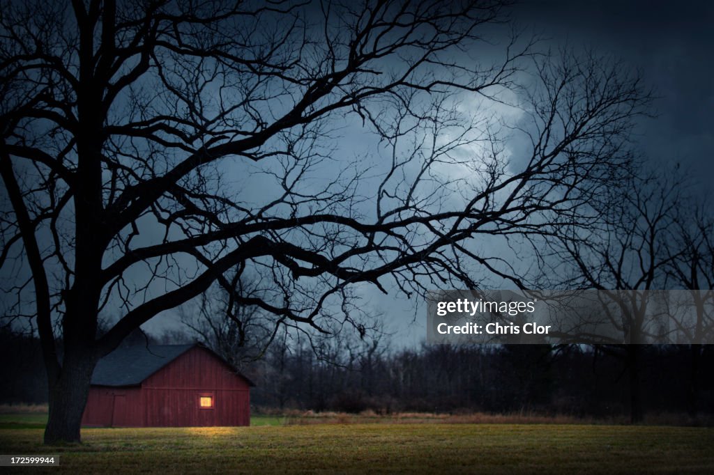 Illuminated barn in rural landscape