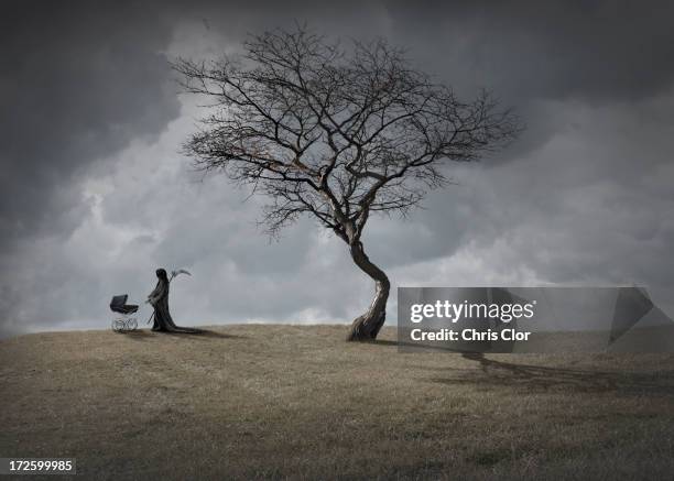 man in black robes with baby carriage by dead tree - scythe stock pictures, royalty-free photos & images