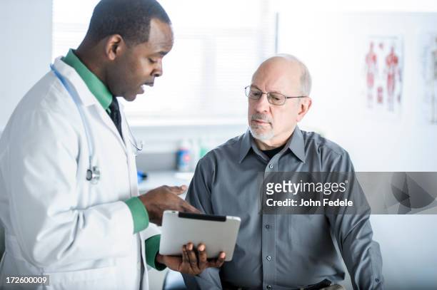 african american doctor talking to patient in office - mannelijk stockfoto's en -beelden