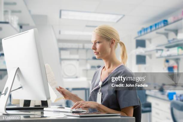 caucasian nurse working at computer in hospital - medisch dossier stockfoto's en -beelden