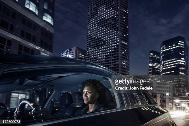 african american woman driving on city street - business person driving stockfoto's en -beelden