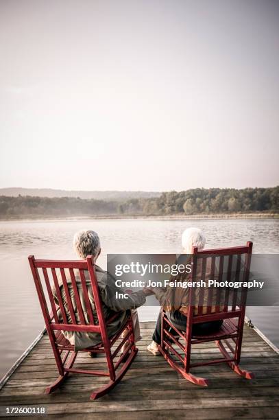 older caucasian couple sitting on wooden dock - rocking chair stock pictures, royalty-free photos & images