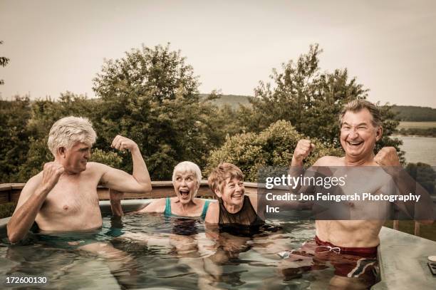 Older Caucasian couples relaxing in swimming pool