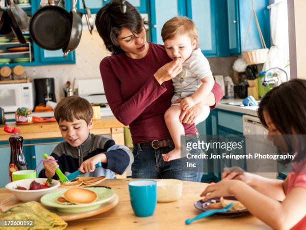 hispanic mother and children having breakfast - sisters feeding bildbanksfoton och bilder