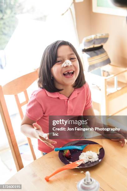 hispanic girl playing with food at table - cream mouth stock-fotos und bilder