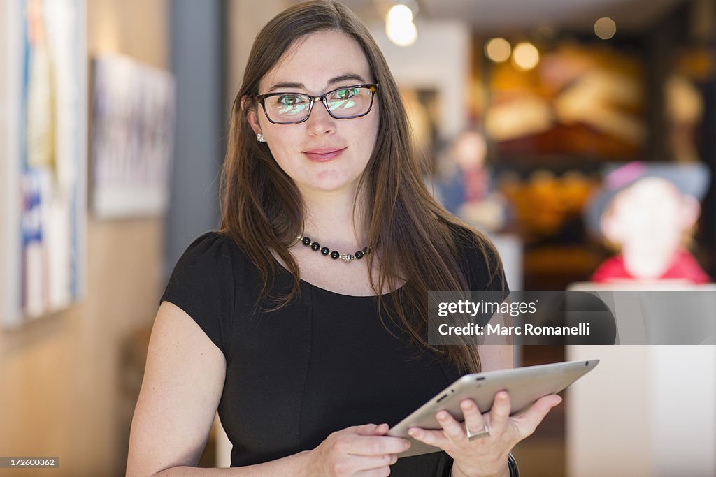Caucasian woman using tablet computer in art gallery