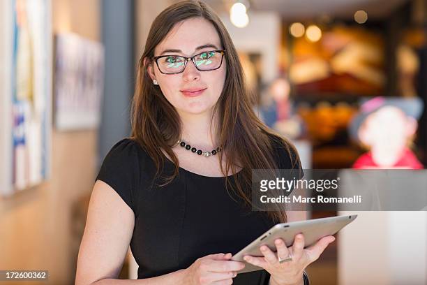 caucasian woman using tablet computer in art gallery - art gallery owner stock pictures, royalty-free photos & images