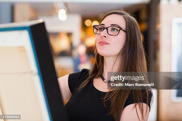 caucasian woman examining painting in art gallery - hanging photos stock pictures, royalty-free photos & images