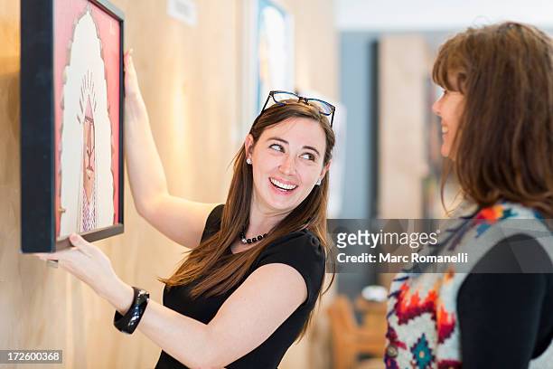 women hanging painting on wall - art gallery owner stock pictures, royalty-free photos & images