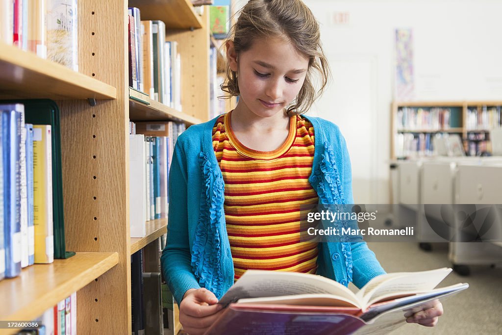 Caucasian girl reading book in library