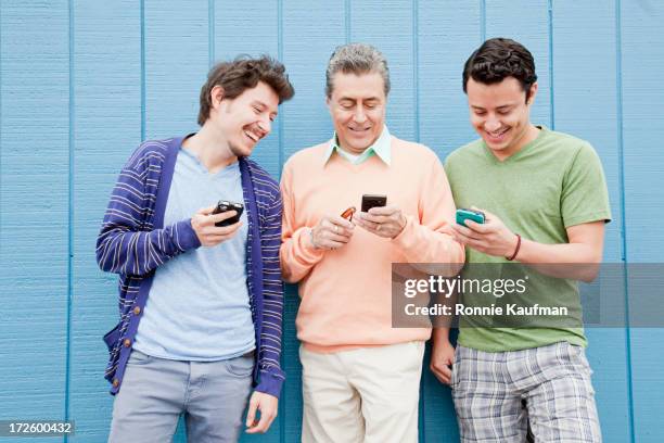 hispanic father and sons using cell phones outdoors - filhos adultos - fotografias e filmes do acervo