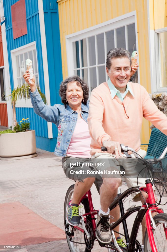 Older Hispanic couple riding tandem bicycle