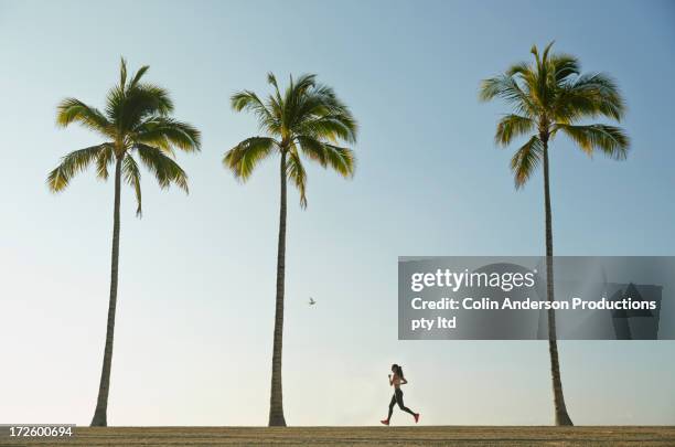 pacific islander woman running on beach - palm tree stock-fotos und bilder