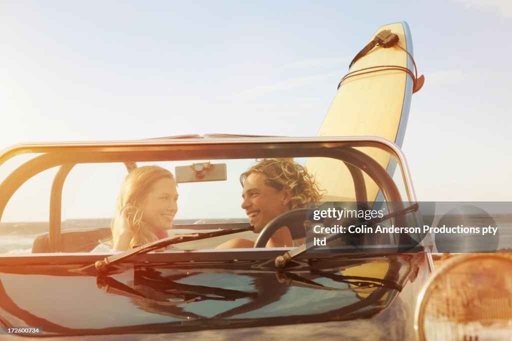 Caucasian couple driving jeep on beach