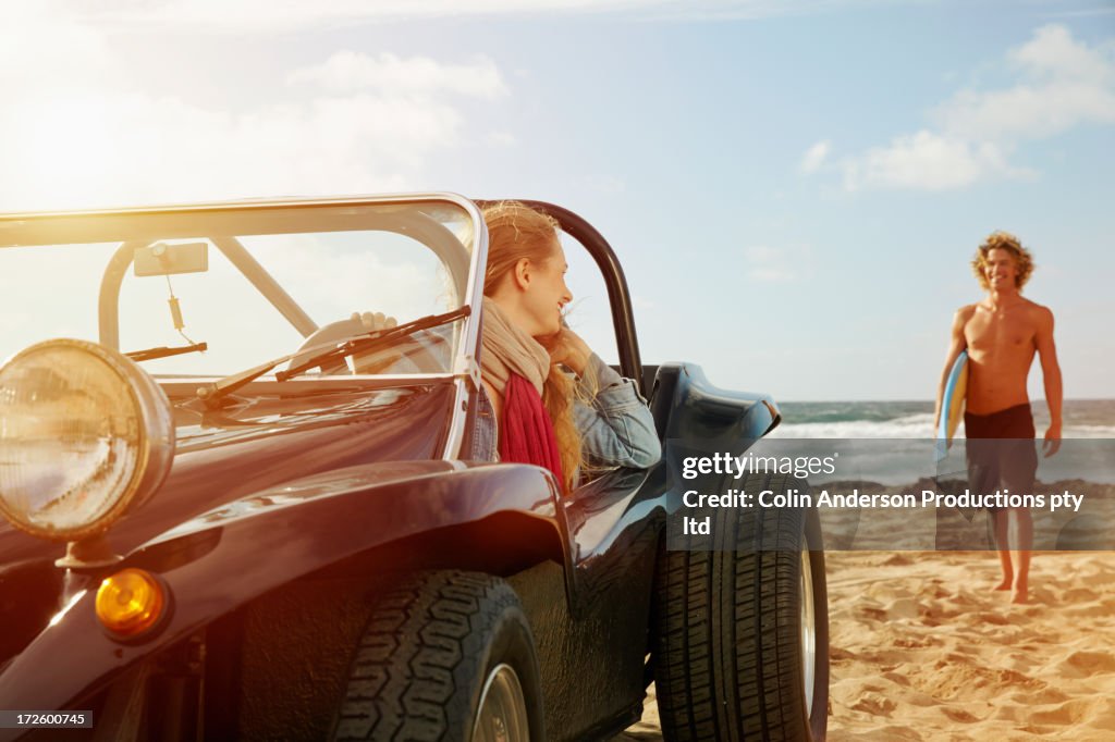 Caucasian woman sitting in jeep on beach