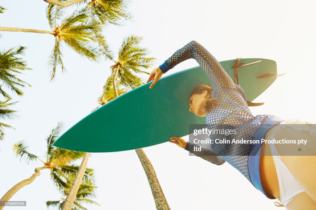 Pacific Islander woman carrying surfboard