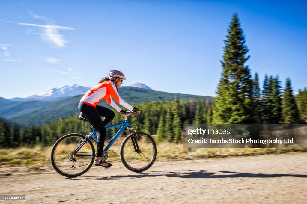 Hispanic woman riding dirt bike in rural landscape