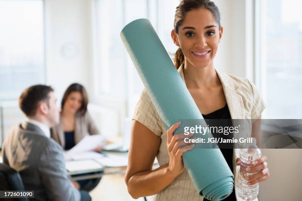 businesswoman holding yoga mat in office - rolled up yoga mat stock pictures, royalty-free photos & images