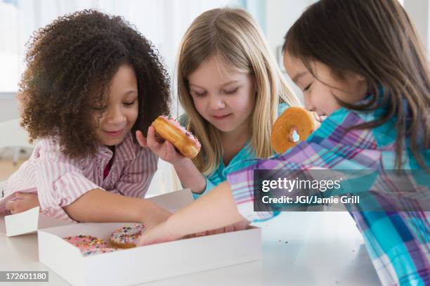 girls eating donuts together in kitchen - friends donut stock pictures, royalty-free photos & images