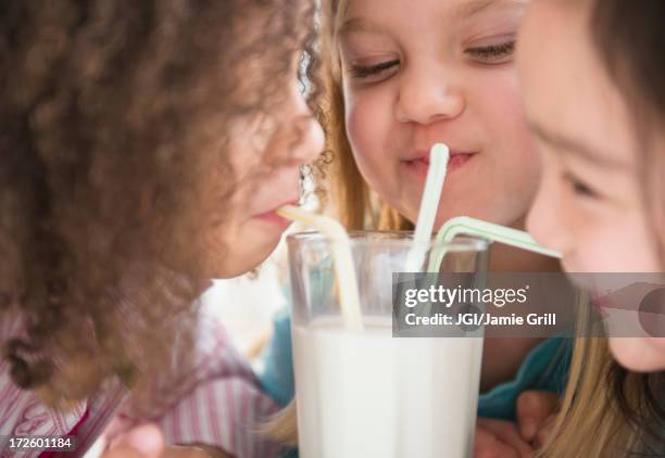 girls sharing glass of milk - drinking straw stock-fotos und bilder