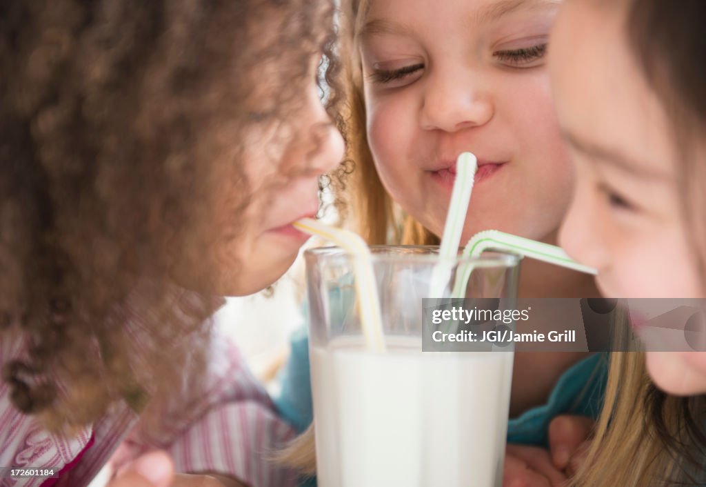 Girls sharing glass of milk