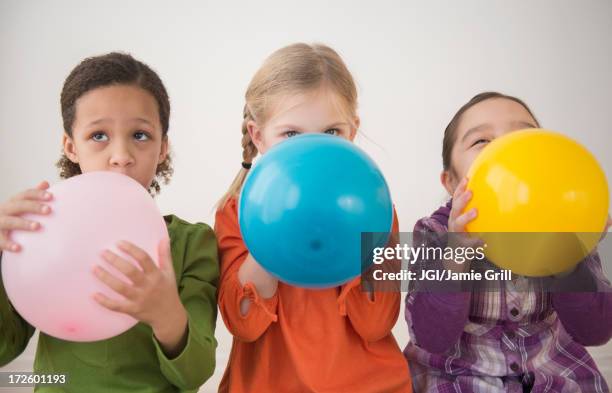 girls blowing balloons together - inflate photos et images de collection