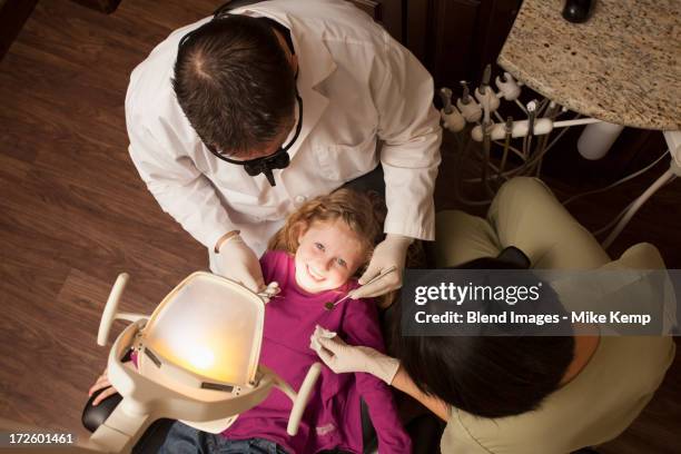 dentist and nurse examining girl's teeth in office - surgical loupes stock pictures, royalty-free photos & images