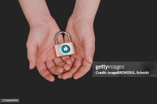 symbolic image of basic child security, child poverty, child in torn clothes symbolically holding a safety lock in his hands, a clock on it, shortly in front of twelve, state support, germany - 政府閉鎖 個照片及圖片檔