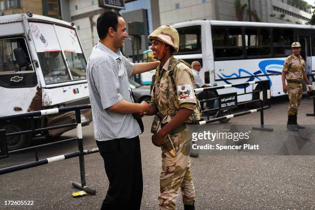 Member of the Egyptian military is greeted in support by a pedestrian in the district of Giza the morning after the first democratically elected...