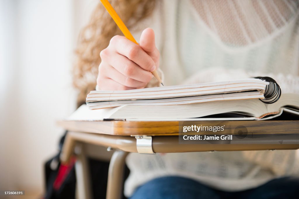 Teenage girl writing in notebook in classroom