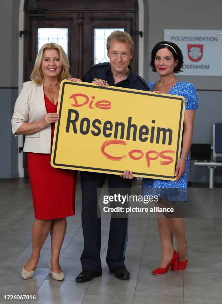 October 2023, Bavaria, Munich: Karin Thaler , Max Müller and Marisa Burger stand at a photo shoot for the TV series "Rosenheim Cops" on the Bavaria...