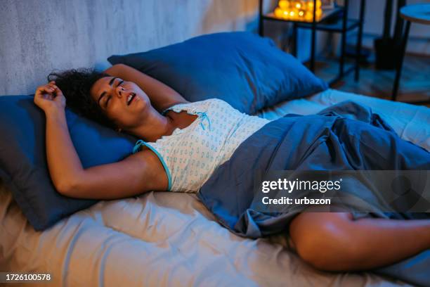 mujer joven durmiendo en la cama por la noche - boca abierta fotografías e imágenes de stock