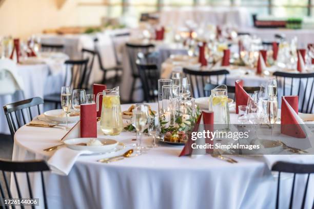 a wedding table covered with a white tablecloth, decorated with flowers, candles, glasses and cutlery. - laying table restaurant stock pictures, royalty-free photos & images