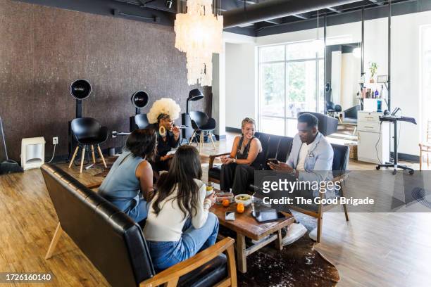 hairstylists sitting together during lunch break at hair salon - male with group of females stock pictures, royalty-free photos & images