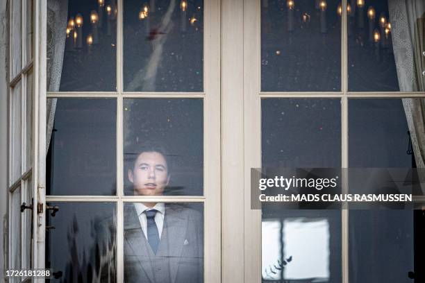 Denmark's Prince Christian looks on from behind the glass door of the balcony of Frederik VIII at Amalienborg Castle in Copenhagen, prior to the...