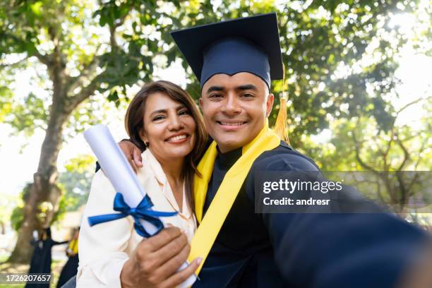 happy graduate taking a selfie with his mother on his graduation day - diverse graduation stock pictures, royalty-free photos & images