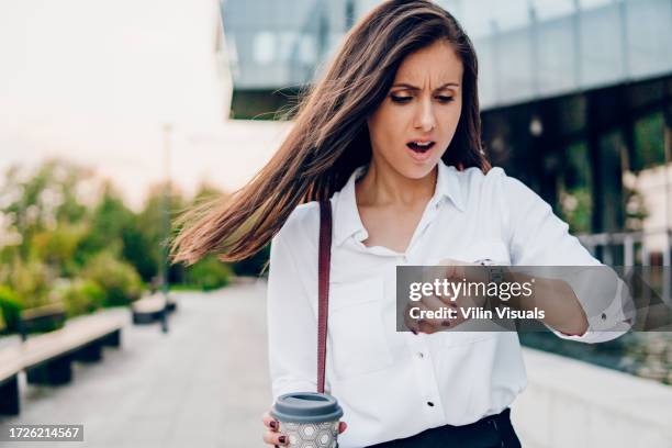 businesswoman looks at her watch and rushes to work - kijken hoe laat het is stockfoto's en -beelden